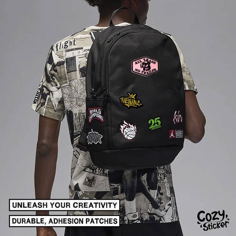 May include: Black backpack adorned with colorful patches, including text and graphic designs. The patches feature phrases like "ALL TRASH NO TRAILER" and "WORLD CHAMPIONS". The backpack has a side pocket and a top handle. The text "UNLEASH YOUR CREATIVITY" and "DURABLE, ADHESION PATCHES" are also visible.