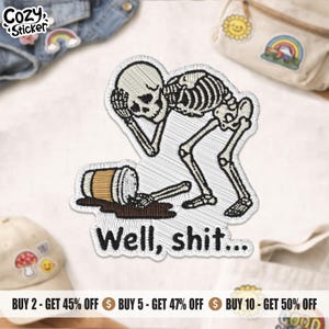 May include: An embroidered patch featuring a white skeleton holding its head in frustration while standing over a spilled brown coffee cup. The text "Well, shit..." is stitched in black thread below the skeleton on a white background.