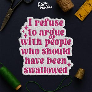 May include: Embroidered patch with the text "I refuse to argue with people who should have been swallowed" in pink lettering. The patch is white with a pink border and star accents. The brand name "Cozy Patches" is at the top.
