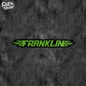 May include: Green embroidered patch with the word "FRANKLIN" in a flame design. The patch is on a dark denim background.