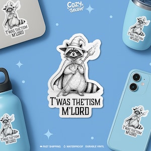 May include: A black and white sticker featuring a raccoon dressed as a wizard, holding a staff. The text "T'WAS THE'TISM M'LORD" is below the raccoon. The sticker is displayed on a laptop, phone, and water bottle.