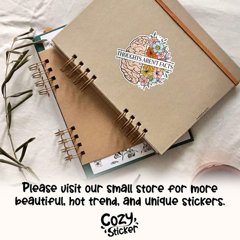 May include: A sticker with a brain design, half in tan and half with colorful flowers, and the text "THOUGHTS AREN'T FACTS". The sticker is on a tan notebook with a spiral binding. The image also includes the text "Please visit our small store for more beautiful, hot trend, and unique stickers."