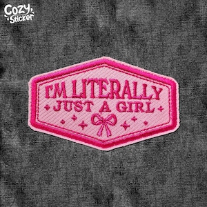 May include: Pink embroidered patch with the text "I'm literally just a girl" in a pink hexagonal shape with a pink bow in the centre.