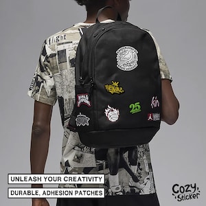 May include: Black backpack adorned with various patches featuring text and graphics, including a bird, basketball, and the number 25. The backpack has a side pocket. The image includes the text: "UNLEASH YOUR CREATIVITY, DURABLE, ADHESION PATCHES."