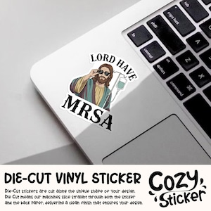 May include: A white die-cut vinyl sticker featuring an illustration of Jesus wearing sunglasses and an IV drip, with the words "LORD HAVE MRSA". The sticker is on a laptop.