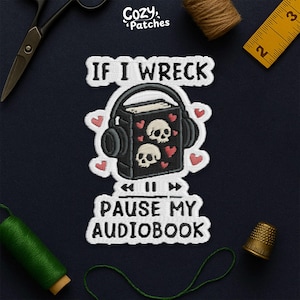 May include: Embroidered patch with the text "IF I WRECK PAUSE MY AUDIOBOOK". The patch features a black book with headphones, two skulls, and hearts. The patch is surrounded by sewing supplies, including scissors, thread, and a thimble.