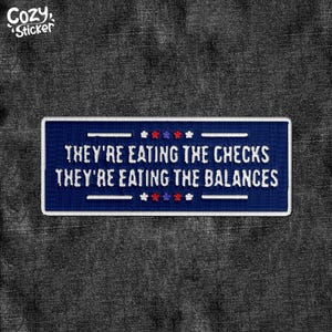 May include: A navy blue patch with white embroidered text that reads "THEY'RE EATING THE CHECKS THEY'RE EATING THE BALANCES." The patch has a white border and is decorated with red, white, and blue stars. The Cozy Sticker logo is in the upper left corner.