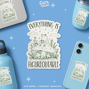 May include: A white sticker with a green illustration of a frog sitting on a mushroom, holding a cup. The sticker has the text "EVERYTHING IS FIGUREOUTABLE" in green. The image also shows the sticker on a laptop, a phone, and a tumbler.