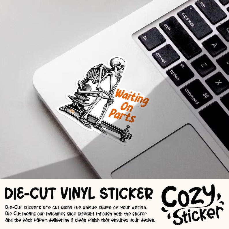 May include: A die-cut vinyl sticker featuring a black and white illustration of a skeleton sitting on a machine, with the text "Waiting On Parts" in orange. The sticker is on a white laptop.