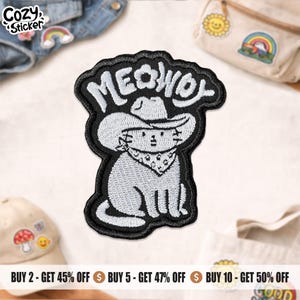 May include: Embroidered patch featuring a cartoon cat wearing a cowboy hat and bandana, with the word "MEOWDY" above. The patch is black with white and gray details, perfect for adding to clothing or accessories.