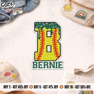 May include: Embroidered patch featuring a yellow baseball-themed letter "B" with red stitching and green accents. The name "BERNIE" is stitched below the letter. The patch has a white border and is likely for clothing or accessories.