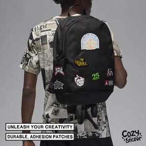 May include: Black backpack decorated with various patches featuring floral, basketball, and text designs. The backpack has a side pocket and is viewed from behind. The image includes the text "UNLEASH YOUR CREATIVITY" and "DURABLE, ADHESION PATCHES."
