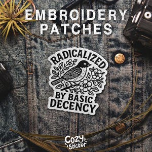 Puede incluir: Parche bordado con un dise&ntilde;o de p&aacute;jaro en blanco y negro, rodeado de flores y las palabras "RADICALIZED BY BASIC DECENCY". El parche est&aacute; sobre una chaqueta vaquera. Las palabras "EMBROIDERY PATCHES" est&aacute;n en la parte superior. El logotipo de Cozy Sticker est&aacute; en la parte inferior.