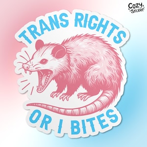 May include: A pink and white sticker with a cartoon opossum with the text "Trans Rights or I Bites" in blue and pink lettering.