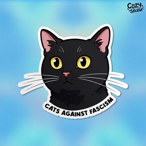 May include: A black cat with yellow eyes and a pink nose looks to the right. The cat is surrounded by a white border with the text "Cats Against Fascism" in black letters.