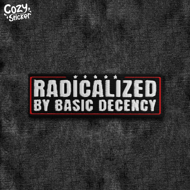 May include: A black patch with the text "RADICALIZED BY BASIC DECENCY" in white, embroidered with a red border. The patch has a small "Cozy Sticker" logo in the upper left corner.