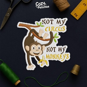 May include: Embroidered patch with a cartoon monkey hanging from a branch, holding a banana. The text "NOT MY CIRCUS NOT MY MONKEYS" is in yellow and white. The patch has a white border and is on a dark blue background.