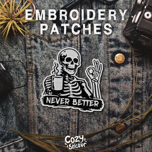 Puede incluir: Parche bordado en blanco y negro con un esqueleto sosteniendo una taza y el texto "NEVER BETTER". El parche est&aacute; sobre una chaqueta vaquera. Las palabras "EMBROIDERY PATCHES" est&aacute;n en la parte superior. El logotipo de Cozy Sticker est&aacute; en la parte inferior.