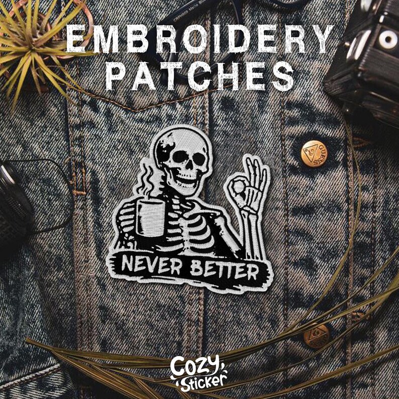 Puede incluir: Parche bordado en blanco y negro con un esqueleto sosteniendo una taza y el texto "NEVER BETTER". El parche est&aacute; sobre una chaqueta vaquera. Las palabras "EMBROIDERY PATCHES" est&aacute;n en la parte superior. El logotipo de Cozy Sticker est&aacute; en la parte inferior.