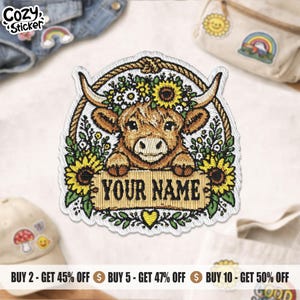 May include: An embroidered patch featuring a brown Highland cow with a floral crown of yellow sunflowers and white daisies. The cow rests its hooves on a rectangular sign with the text YOUR NAME, framed by a rope border and a small yellow heart.