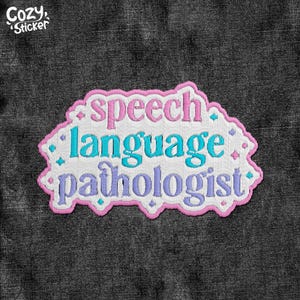 Peut inclure: Écusson brodé avec les mots "speech language pathologist" en rose, turquoise et violet. Le patch a un fond blanc avec une bordure rose et est décoré de petits losanges turquoise et roses. Le patch est sur un fond en denim gris foncé.