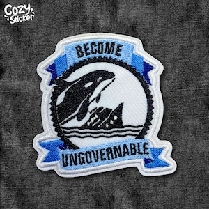 May include: Embroidered patch featuring a black and white orca breaching from the ocean, set against a white background. The patch has a blue banner at the top with the word "BECOME" and a banner at the bottom with "UNGOVERNABLE". The patch is bordered in white.