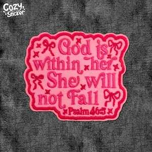 May include: A pink embroidered patch with the text "God is within her, She will not Fall" and "Psalm 46:5" in a decorative font. The patch has a scalloped edge and bow accents. The patch is on a dark grey denim background.