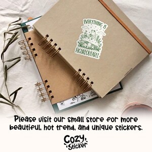 May include: Two spiral-bound notebooks with kraft paper covers are stacked. A sticker with a frog on a mushroom and the words "EVERYTHING IS FIGUREOUTABLE" is on the top notebook. The bottom notebook has a green cover.