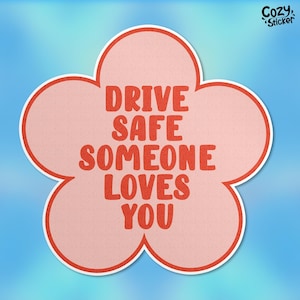 Peut inclure: Un autocollant en forme de fleur avec un centre rose clair et une bordure blanche. L'autocollant porte les mots "DRIVE SAFE SOMEONE LOVES YOU" en lettres rouges et grasses. L'autocollant est sur un fond dégradé bleu.