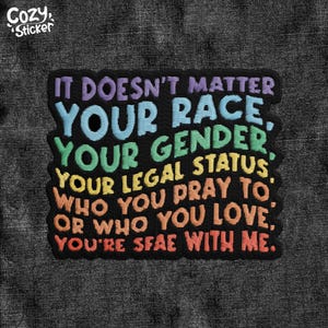 May include: A black embroidered patch with the text "IT DOESN'T MATTER YOUR RACE, YOUR GENDER, YOUR LEGAL STATUS, WHO YOU PRAY TO, OR WHO YOU LOVE, YOU'RE SAFE WITH ME." The patch has a colorful, rainbow-like design.
