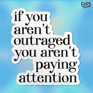 May include: White sticker with black text that reads "if you aren't outraged you aren't paying attention".