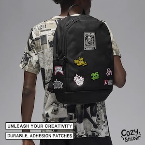 K&ouml;nnte beinhalten: Schwarzer Rucksack mit bunten Aufn&auml;hern, darunter ein Basketball, ein Sensenmann und die Zahl 25. Der Rucksack hat eine Seitentasche und wird von einer Person getragen. Der Text "UNLEASH YOUR CREATIVITY" und "DURABLE, ADHESION PATCHES" sind sichtbar.