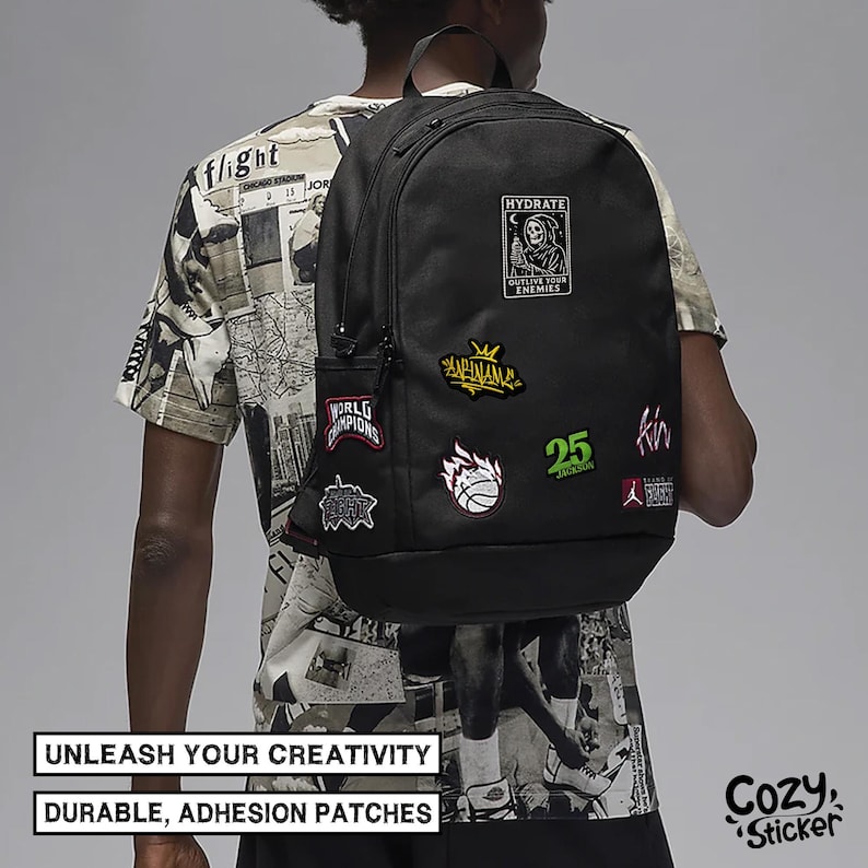 K&ouml;nnte beinhalten: Schwarzer Rucksack mit bunten Aufn&auml;hern, darunter ein Basketball, ein Sensenmann und die Zahl 25. Der Rucksack hat eine Seitentasche und wird von einer Person getragen. Der Text "UNLEASH YOUR CREATIVITY" und "DURABLE, ADHESION PATCHES" sind sichtbar.
