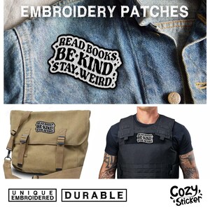 May include: A white embroidered patch with black text that reads "Read Books Be Kind Stay Weird". The patch is shown on a blue denim jacket, a tan messenger bag, and a black tactical vest. The text "Unique Embroidered Durable Cozy Sticker" is also shown in the image.