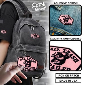May include: Pink embroidered patch with the text "ALL TRASH NO TRAILER" and a raccoon illustration. The patch is shown on a backpack and denim jacket. The image also includes the text "Cozy Sticker", "Adhesive Design", "Exquisite Embroidered", "Iron on Patch", and "Made in USA".