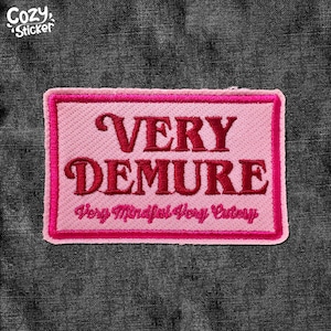 May include: Pink and red embroidered patch with the text "VERY DEMURE" and the smaller text "Very Mindful Very Cute" below.