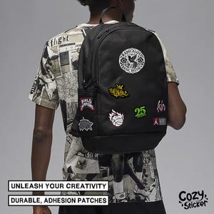 Puede incluir: Mochila negra con varios parches, incluyendo un dise&ntilde;o floral y una pelota de baloncesto. La mochila tiene un bolsillo lateral y se lleva sobre los hombros. El texto de la imagen dice: "UNLEASH YOUR CREATIVITY" y "DURABLE, ADHESION PATCHES."