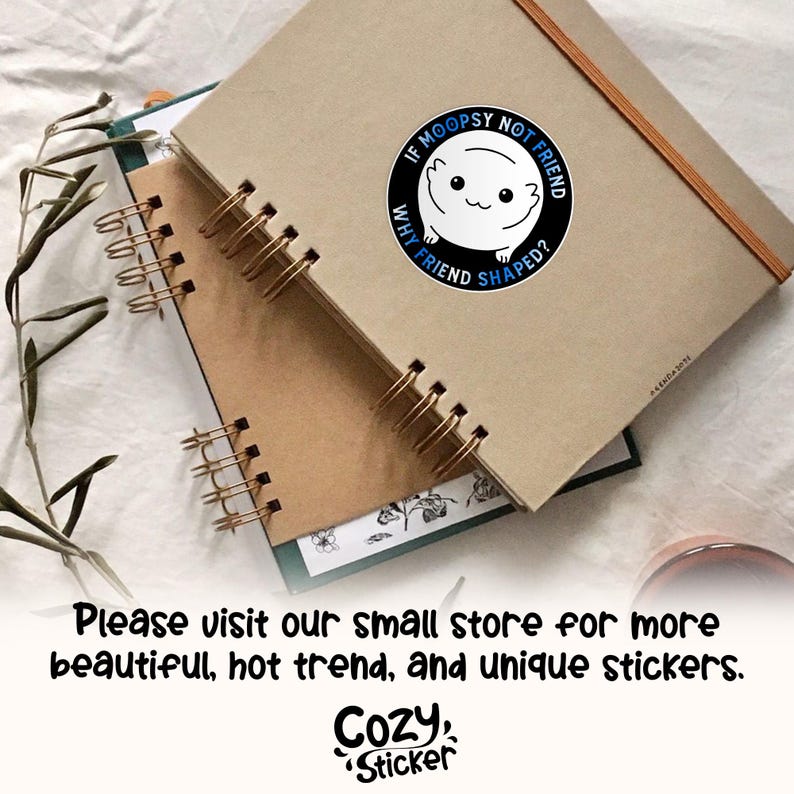 May include: A black and white sticker featuring a cartoon animal with the text "If Moopsy Not Friend Why Friend Shaped?" The sticker is on a brown notebook with a spiral binding.