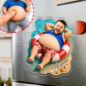 May include: A custom acrylic refrigerator magnet featuring a photo of a person in a blue tank top and red patterned swim trunks floating in a red and white inner tube on ocean water, with the text Anyname written in black script on the sand.