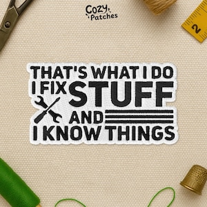May include: Embroidered patch with the text "THAT'S WHAT I DO I FIX STUFF AND I KNOW THINGS" in black on a white background. A crossed wrench and screwdriver graphic is included. The patch is from Cozy Patches.