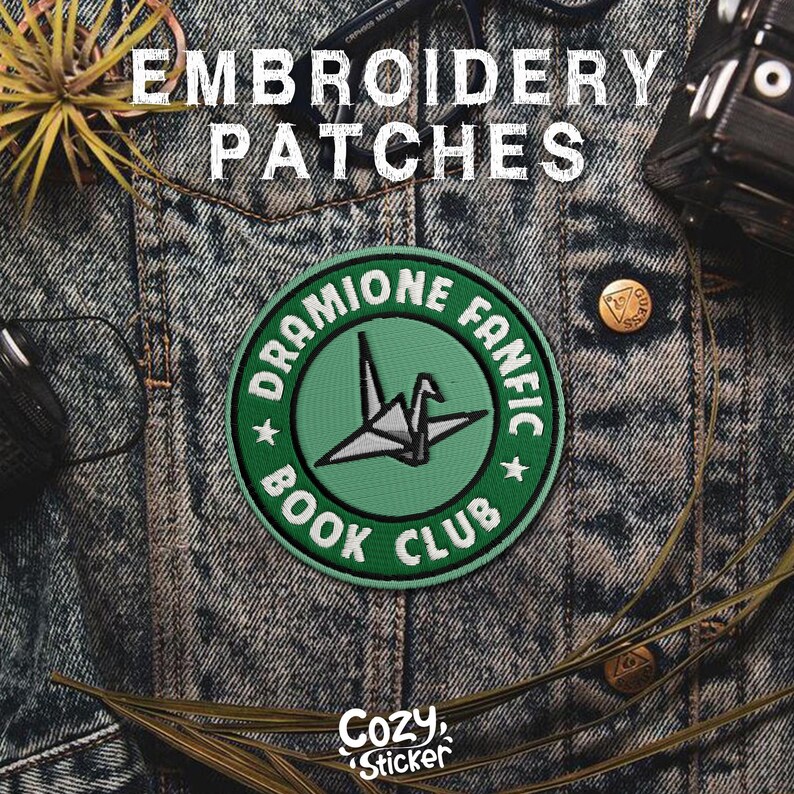 Puede incluir: Un parche bordado verde y blanco con el texto "Dramione Fanfic Book Club" y un dise&ntilde;o de grulla de papel. El parche es circular y est&aacute; colocado sobre una chaqueta vaquera. La palabra "Embroidery Patches" est&aacute; en la parte superior.
