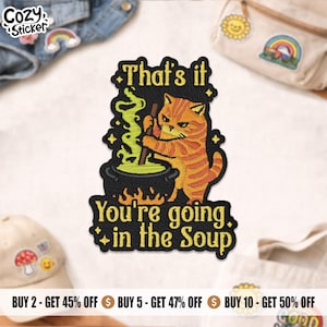 May include: Embroidered patch featuring an orange tabby cat stirring a cauldron of green liquid. The patch reads "That's it, You're going in the Soup" in yellow text with black outlines. The patch has a black border and is decorated with yellow stars.