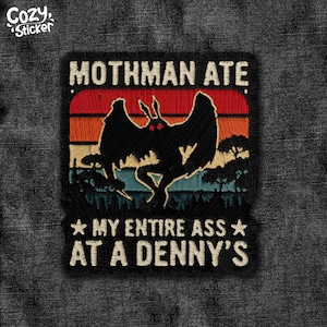 May include: Embroidered patch featuring a black Mothman silhouette with red eyes against a sunset backdrop. Text reads "Mothman Ate My Entire Ass At A Denny's". The patch has a vintage, distressed aesthetic.