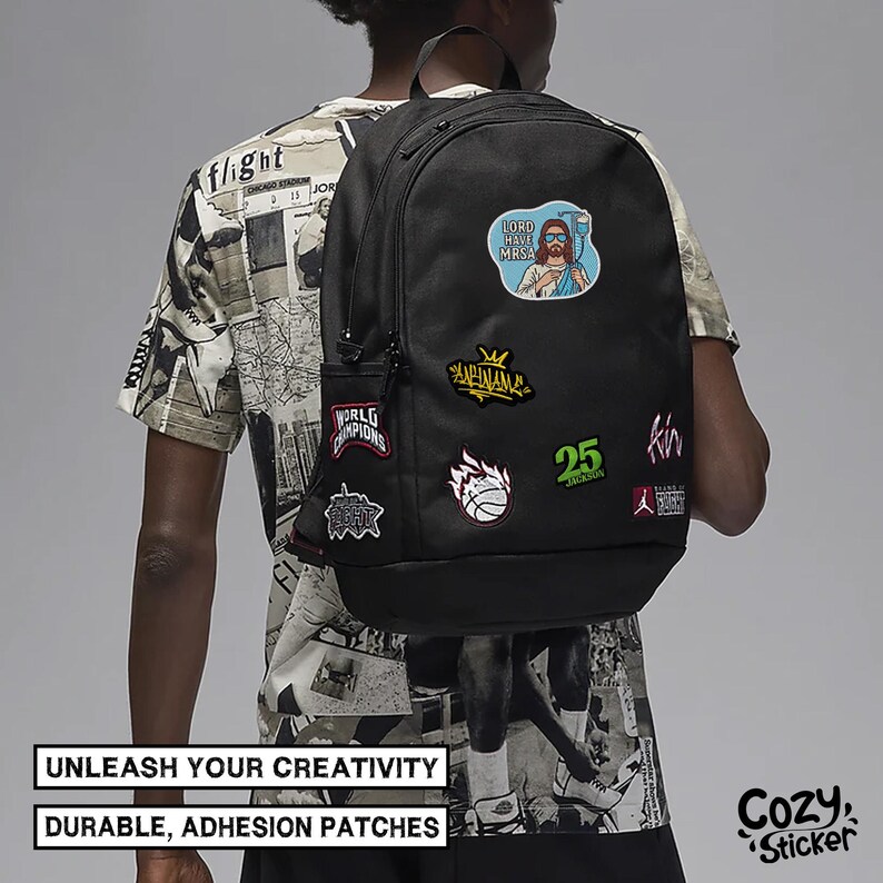 Puede incluir: Mochila negra adornada con parches coloridos, incluyendo una caricatura con el texto "LORD HAVE MRSA". La mochila tambi&eacute;n presenta parches con texto y gr&aacute;ficos. La imagen incluye el texto "UNLEASH YOUR CREATIVITY" y "DURABLE, ADHESION PATCHES".