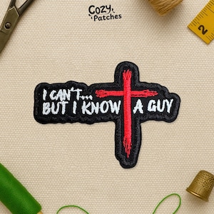 May include: Black embroidered patch with the text "I CAN'T... BUT I KNOW A GUY" in white, and a red cross design. The patch is surrounded by a black border. The patch is on a beige background.