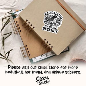 May include: A sticker with the text "RADICALIZED BY BASIC DECENCY" and a black and white bird illustration, placed on a brown notebook. The notebook is spiral-bound with gold-colored coils. The image also includes the text "Please visit our small store for more beautiful, hot trend, and unique stickers."