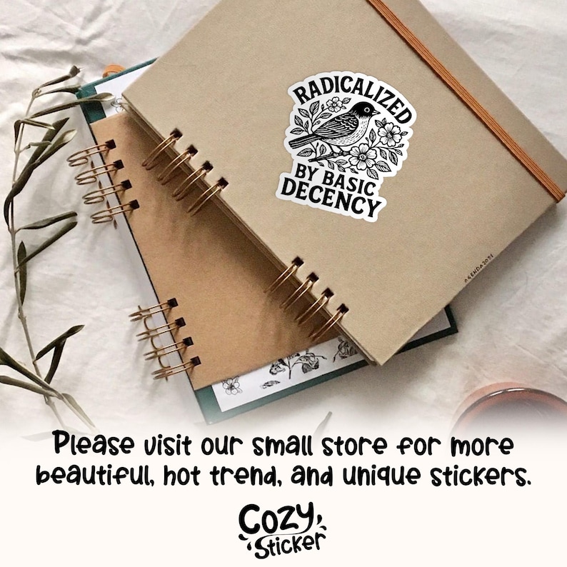 May include: A sticker with the text "RADICALIZED BY BASIC DECENCY" and a black and white bird illustration, placed on a brown notebook. The notebook is spiral-bound with gold-colored coils. The image also includes the text "Please visit our small store for more beautiful, hot trend, and unique stickers."