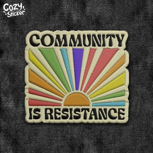 May include: Embroidered patch with the text "COMMUNITY IS RESISTANCE" in black. The design features a colorful sunburst in shades of orange, yellow, green, blue, and pink. The patch has a cream-colored border and the brand name "Cozy Sticker" in the upper left corner.