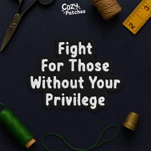 May include: Black and white embroidered patch with the text "Fight For Those Without Your Privilege." The patch is surrounded by sewing tools, including scissors, a thimble, and measuring tape. The brand name "Cozy Patches" is in the top left corner.
