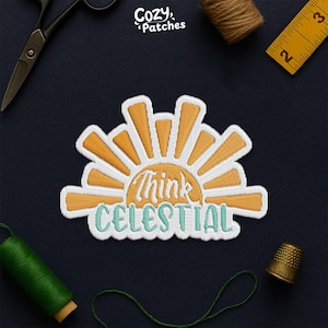May include: Embroidered patch featuring a stylized sunburst design with the words "Think Celestial" in a script font. The patch has a white border, orange and white sun rays, and teal lettering. The patch is surrounded by sewing tools.